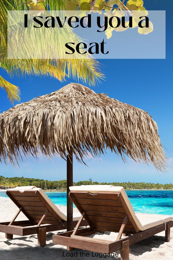 Two lounge chairs on the beach with a thatched umbrella.  The words I saved you a seat